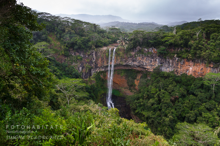 Wasserfall über gebogenen Felsen im Dschungel